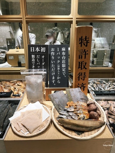 昆布・椎茸・かつお節をかごに並べただし尾粂の売り場と、見本のだしパック