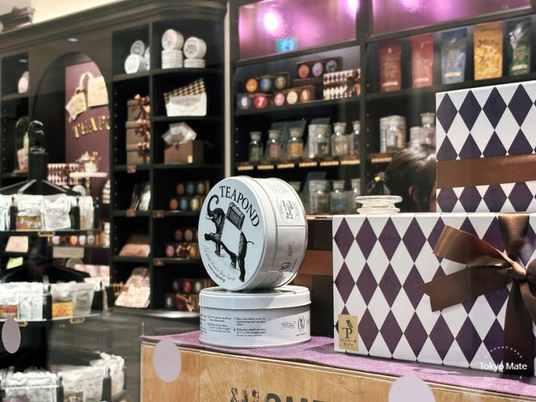 店の棚を背にしたTEAPONDの紅茶缶と、ダイヤ柄のギフトボックス