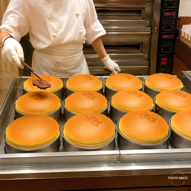 Staff stamping the Rikuro Ojisan face onto a freshly baked cheesecake