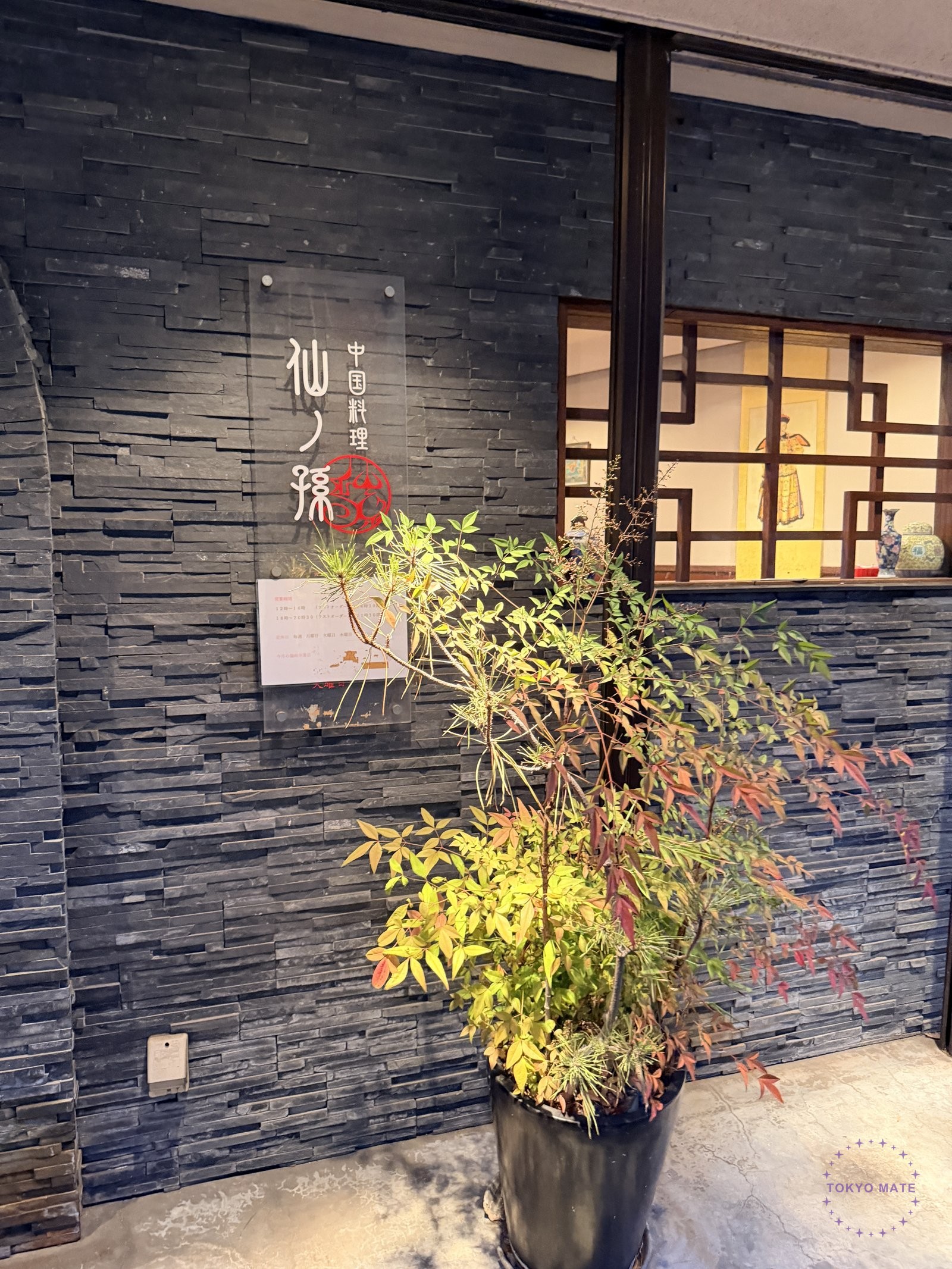 Sennomago entrance with black stone wall and acrylic sign