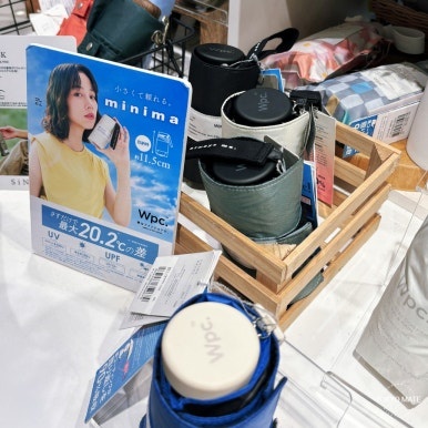 Wpc. MINIMA 6-fold parasols in a store basket beside the 11.5cm display sign